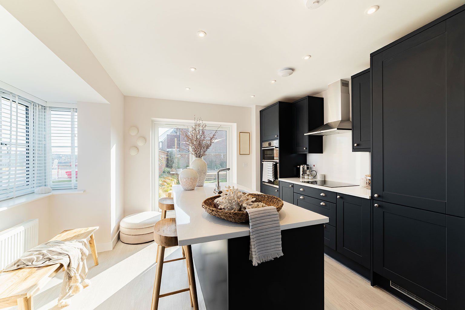 Bright contemporary kitchen with black cabinets, a central island, and natural light from bay windows
