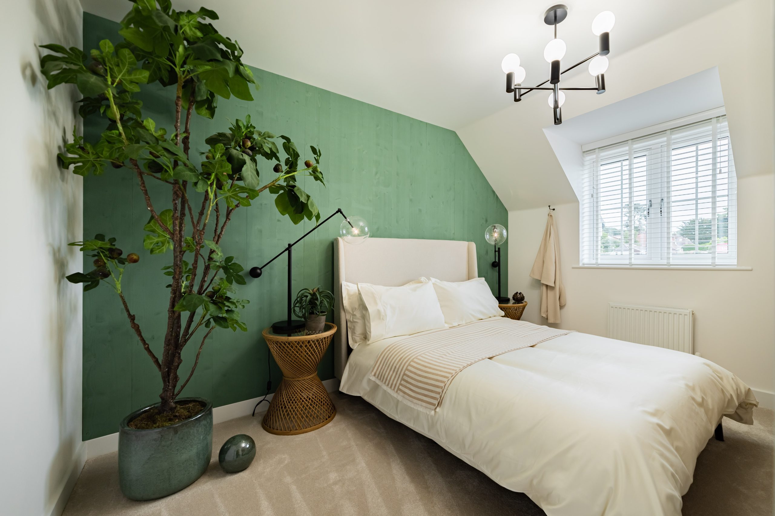 Contemporary bedroom with green feature wall, large potted plant, white bedding, and modern chandelier