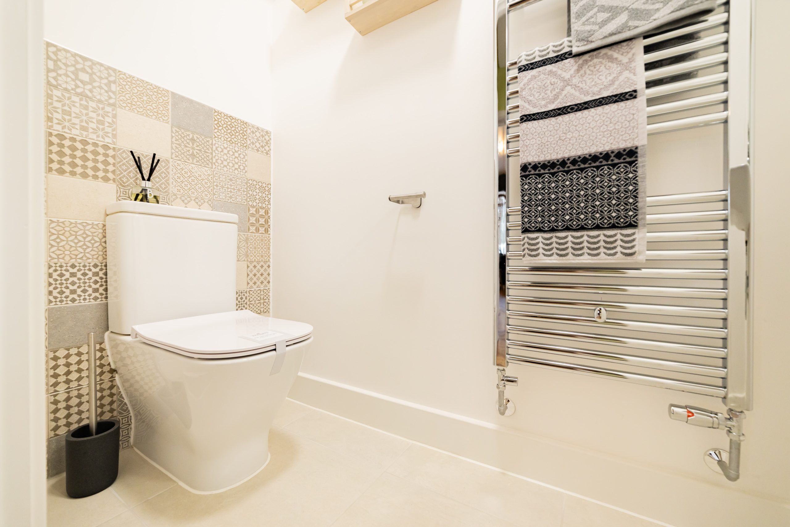 Bathroom with toilet, bath and textured tiled wall