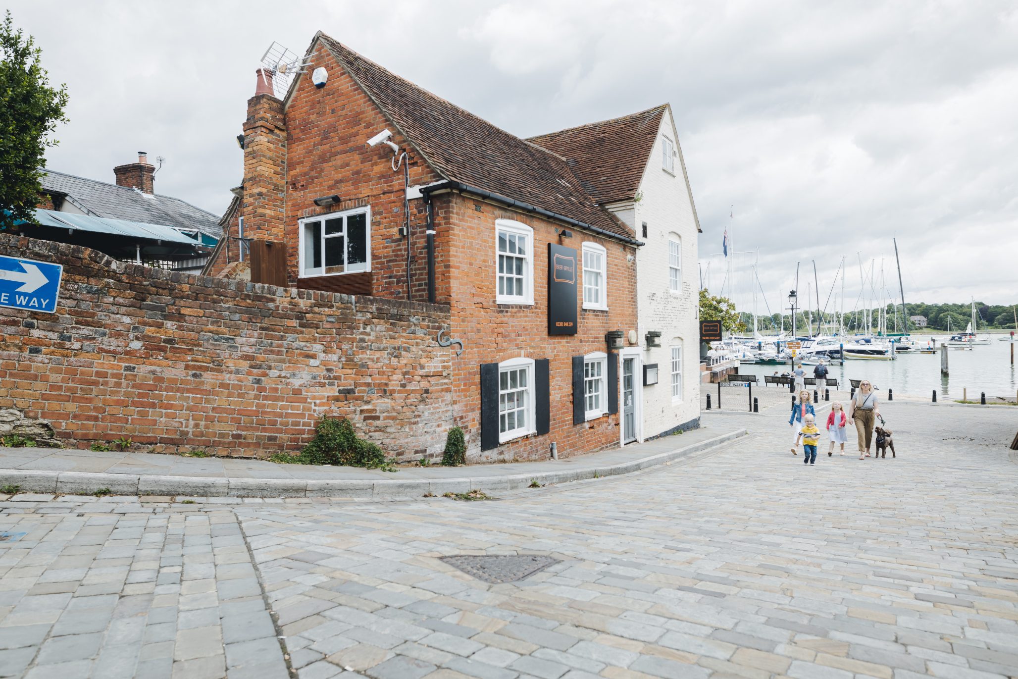 Historic brick and white-painted building on a cobbled street near a marina